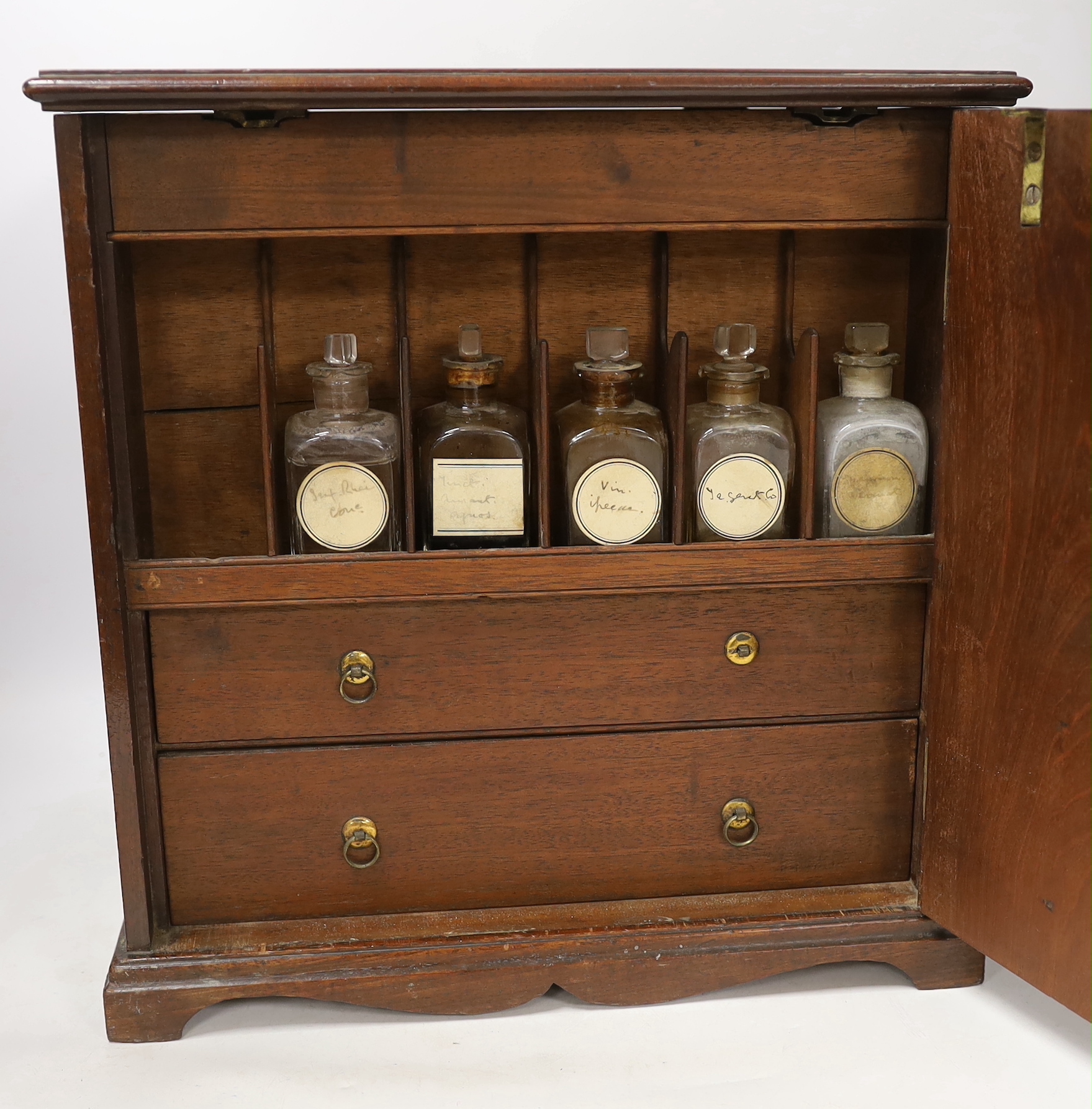 An early 19th century mahogany apothecary box, opening on both opposite sides and top lid, with fitted compartments and two drawers containing square section labelled glass bottles, oak and zinc lidded drawer sections, c